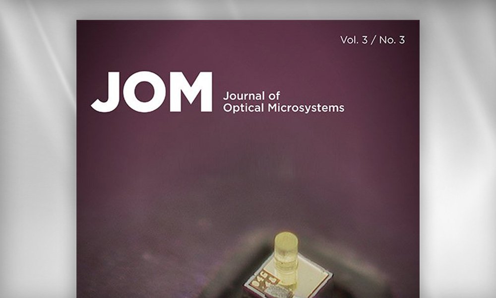 SPIE Journal cover of JOM: Journal of Optical Microsystems showing a close-up of a microfabricated optical component on a chip against a dark purple gradient background.